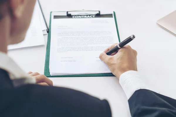 Image view cross shoulder to seeing young businessman handle a pen to sign in contract paper on table, copy space, business concept