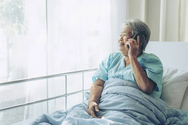 Elderly patients in hospital bed patients using smart phone call to descendant relatives feel happiness - medical and healthcare concept