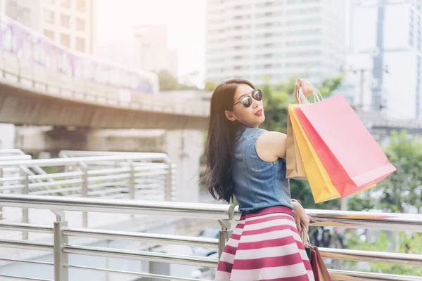 買い物や紙袋を持って後に陽気な若いアジアの女性 — ストック写真