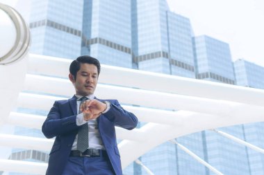 Orta yaşlı Asyalı işadamı yoğun saatlerde kol saatine baktı. Şehirdeki modern binaların arka planlarını bulanıklaştırdı. Uzayı kopyaladı.