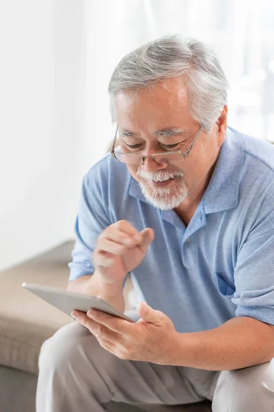 Senior Asian man using a smartphone , smiling feel happy on sofa at home - lifestyle senior elderly people concept