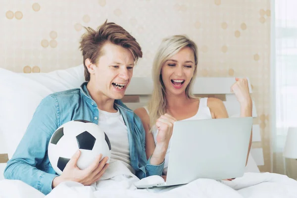 若いカップルハンサムな夫と美しい妻は 彼らが応援するサッカーがベッドルームで優勝チャンピオンであるときに素晴らしい感じ ライフスタイル愛のカップルのコンセプト — ストック写真