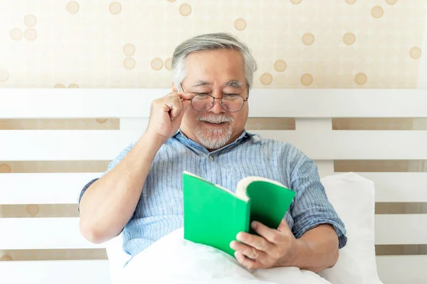 Senior Άνδρας Ηλικιωμένος Άνδρας Γυαλιά Διαβάζει Ένα Μυθιστόρημα Στο Κρεβάτι — Φωτογραφία Αρχείου