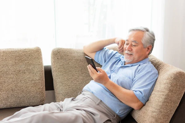 Senior Αρσενικό Χρησιμοποιώντας Ένα Smartphone Χαμογελώντας Αισθάνονται Ευτυχισμένοι Στον Καναπέ — Φωτογραφία Αρχείου