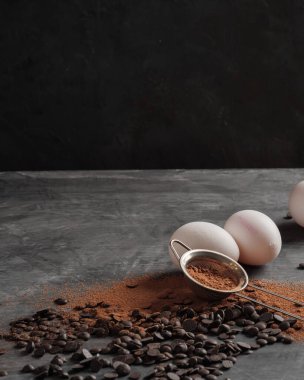 Çikolata parçacıkları, kakao tozu, tavuk yumurtaları gri bir arka planda gri bir bez parçası. Uzayı kopyala Dikey fotoğraf.
