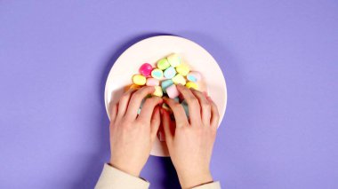 Elleri tabakta şeker alıyor.