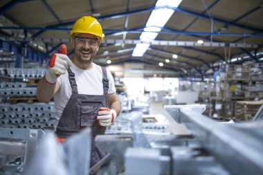 Fabrika işçisinin portresi. Koruyucu ekipman. Prodüksiyon salonunda baş parmak tutuyor..