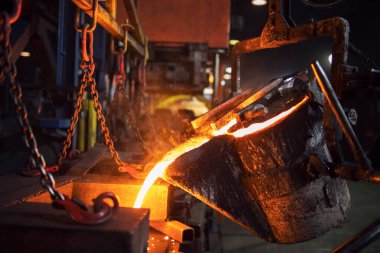 Dökümhane kovası döküm kalıbına sıcak erimiş metal döküyor. Metalurji ve çelik üretimi.