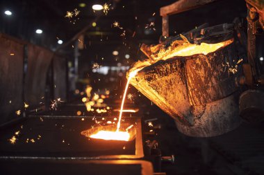 Dökümhanede erimiş metal dökümü. Küfü sıcak sıvı demirle doldurmak ve çelik fabrikasında demir bileşenleri üretmek..