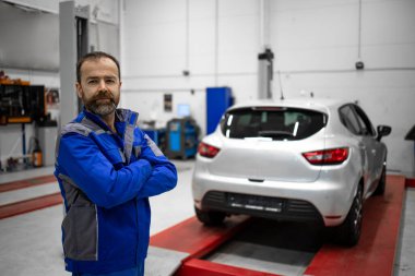 Hizmet ve bakım için araç atölyesinde duran orta yaşlı bir araba tamircisinin portresi.