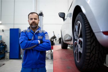 Araba tamircisinin portresi bir otomobil atölyesinde duruyor..