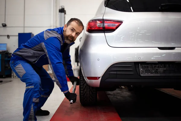 Araç atölyesinde çalışan profesyonel araba tamircisi otomobilin bakımını ve bakımını yapıyor..