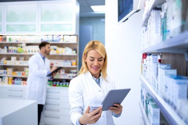 Eczanede iş arkadaşıyla birlikte çalışan beyaz önlüklü güzel bir kadın eczacı..