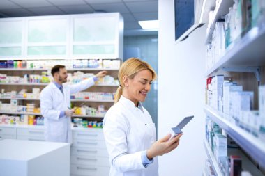 Eczanede çalışan beyaz önlüklü eczacı. İlaçlar satışa hazırlanıyor.