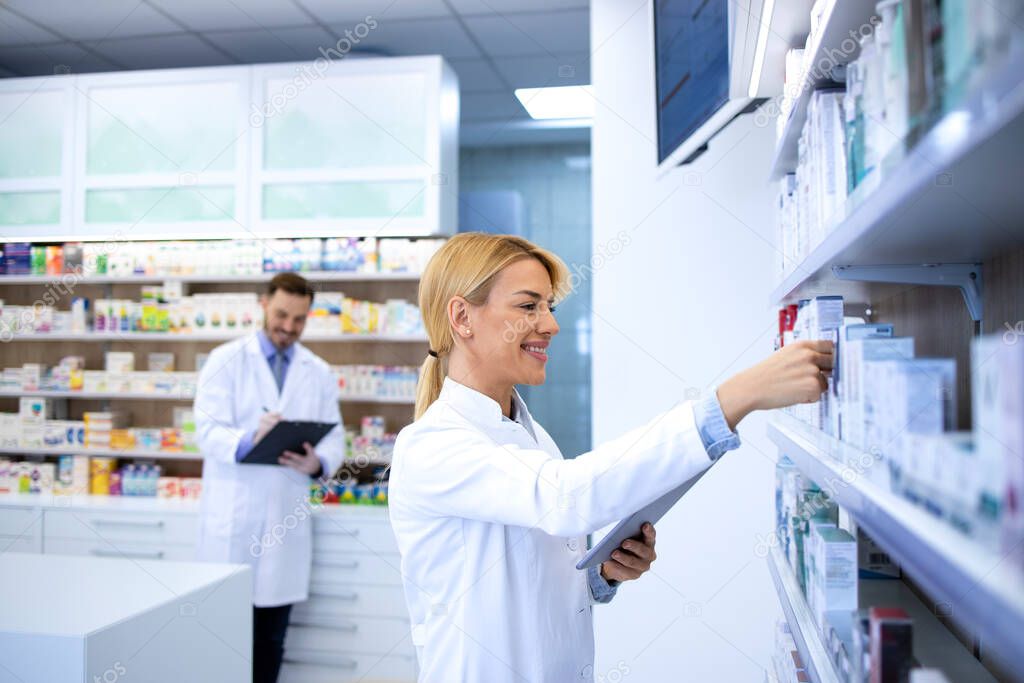 Female pharmacist working in the pharmacy shop and arranging medicines on the shelf.