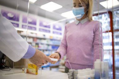Eczacı, covid-19 virüs salgını sırasında eczanedeki müşterilere vitamin ve ilaç satıyor..