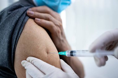 Corona virüsü salgını sırasında yaşlı bir adamın koluna aşı vurulmasını yakından izleyin..