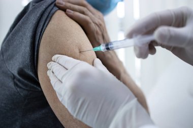 Corona virüsü salgını sırasında yaşlı bir adamın koluna aşı vurulmasını yakından izleyin..