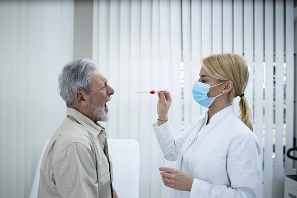 Epidemiologist taking PCR test of an elderly patient during COVID-19 pandemic.