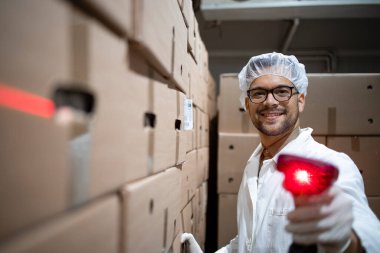 Yiyecek deposunda barkod tarayıcısı tutan saç filesi ve hijyenik eldivenli fabrika işçisinin portresi..