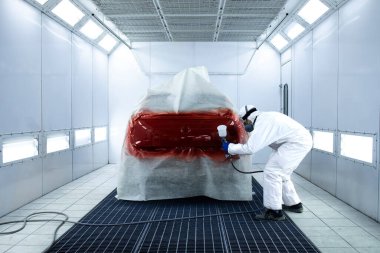 Araba boyacısı boyama odasının atölyesinde araç cilalıyor..