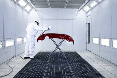 Koruyucu giysiler içinde araba boyacısı ve otomobil boyama tamponunda metalik boya ve oda atölyesinde cila..