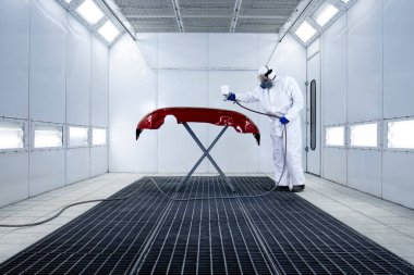 Koruyucu giysiler içinde araba boyacısı ve otomobil boyama tamponunda metalik boya ve oda atölyesinde cila..