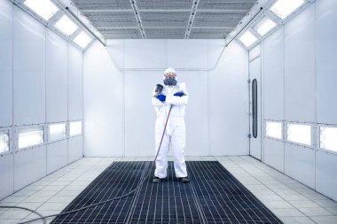 Boyacının portresi boya odası atölyesinde elinde boya tabancasıyla duruyor..