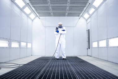 Boyacının portresi boya odası atölyesinde elinde boya tabancasıyla duruyor..