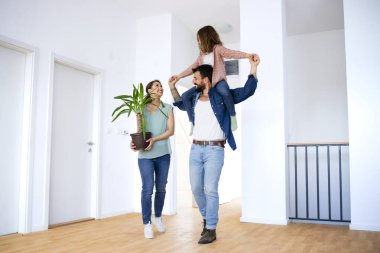 Father carrying daughter piggyback while moving into new apartment.