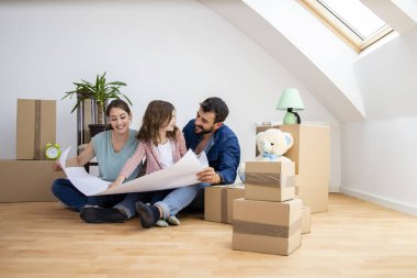 House moving concept - family looking at real estate project layout and little girl showing her bedroom.