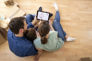 House moving concept - top view of happy family choosing house interior design on tablet computer.
