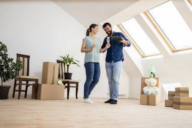 Young caucasian couple dancing and drinking champagne to celebrate moving into new home.