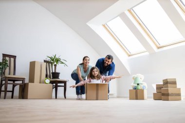 Happy family and children having fun with cardboard boxes in new house at moving day.