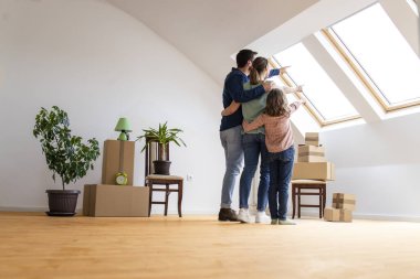 Happy family hugging together and looking through window of the new house.