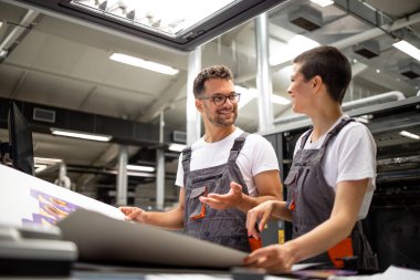 Baskı işçileri üretim fabrikasında baskı kalitesi hakkında tartışıyorlar.