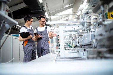 Üretim hattı işçileri fabrikadaki modern ambalaj makinesinin üretim sürecini kontrol ediyorlar.