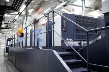 Modern ofset baskı makinesi ile fabrika iç yazıcı ve etrafında çalışan meşgul insanlar.