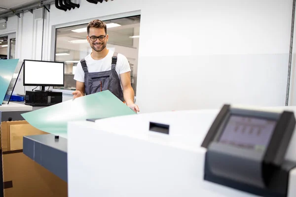 印刷所の機械を板金するためにコンピュータを操作する笑顔印刷労働者 — ストック写真