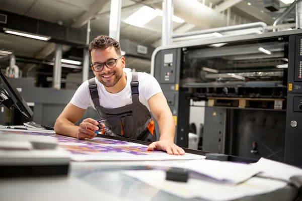 印刷家の労働者は 印刷プロセスの品質を制御し 虫眼鏡で色をチェック — ストック写真