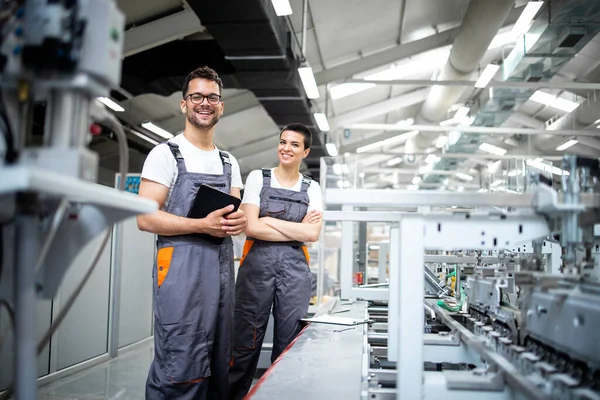 Baskı fabrikasındaki modern ambalaj makinesinin üretim sürecini kontrol eden üretim hattı işçilerinin portresi.