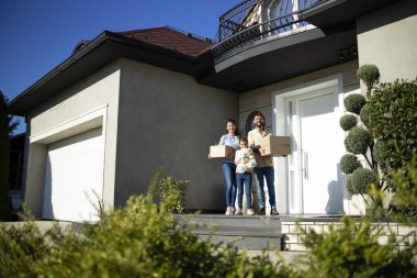 Yeni evlerinin verandasında taşınmaya hazır mutlu beyaz bir ailenin portresi..