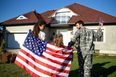 Mutlu askeri aile Amerikan bayrağı taşıyor ve eve hoş geldin baba asker.