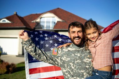 Asker üniformalı asker babasının portresi. Güzel kızını ve Amerikan bayrağını evlerinin önünde tutuyor..