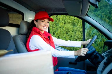 Paketler ön koltukta, paketleri zamanında teslim etmek için hızlı giden kadın kurye minibüsü..