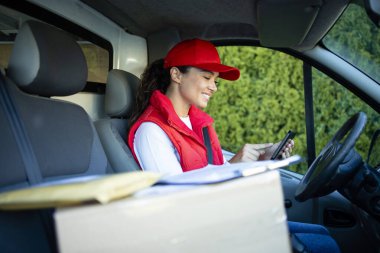 Dişi kurye teslimattan önce dijital tabletteki paketleri kontrol ediyor.