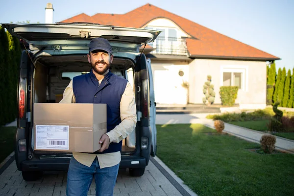 Kurye paketini tutuyor ve evin önündeki vajinasının yanında teslimata hazır bekliyor..