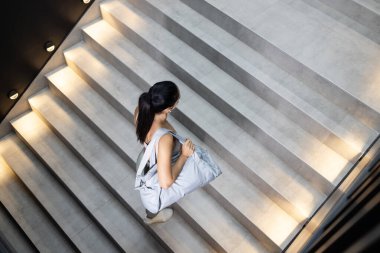 Kafkasyalı kadın spor çantası taşıyor ve merdivenlerde eğitime gidiyor..