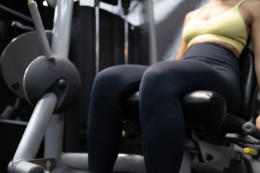 Sporcu spor salonunda bacak eğitimi için egzersiz makinesi kullanıyor..