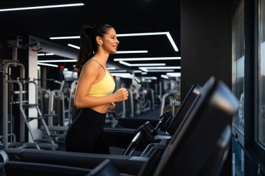 İyi donanımlı spor salonunda koşu bandında koşan kadın sporcu ya da stajyer..
